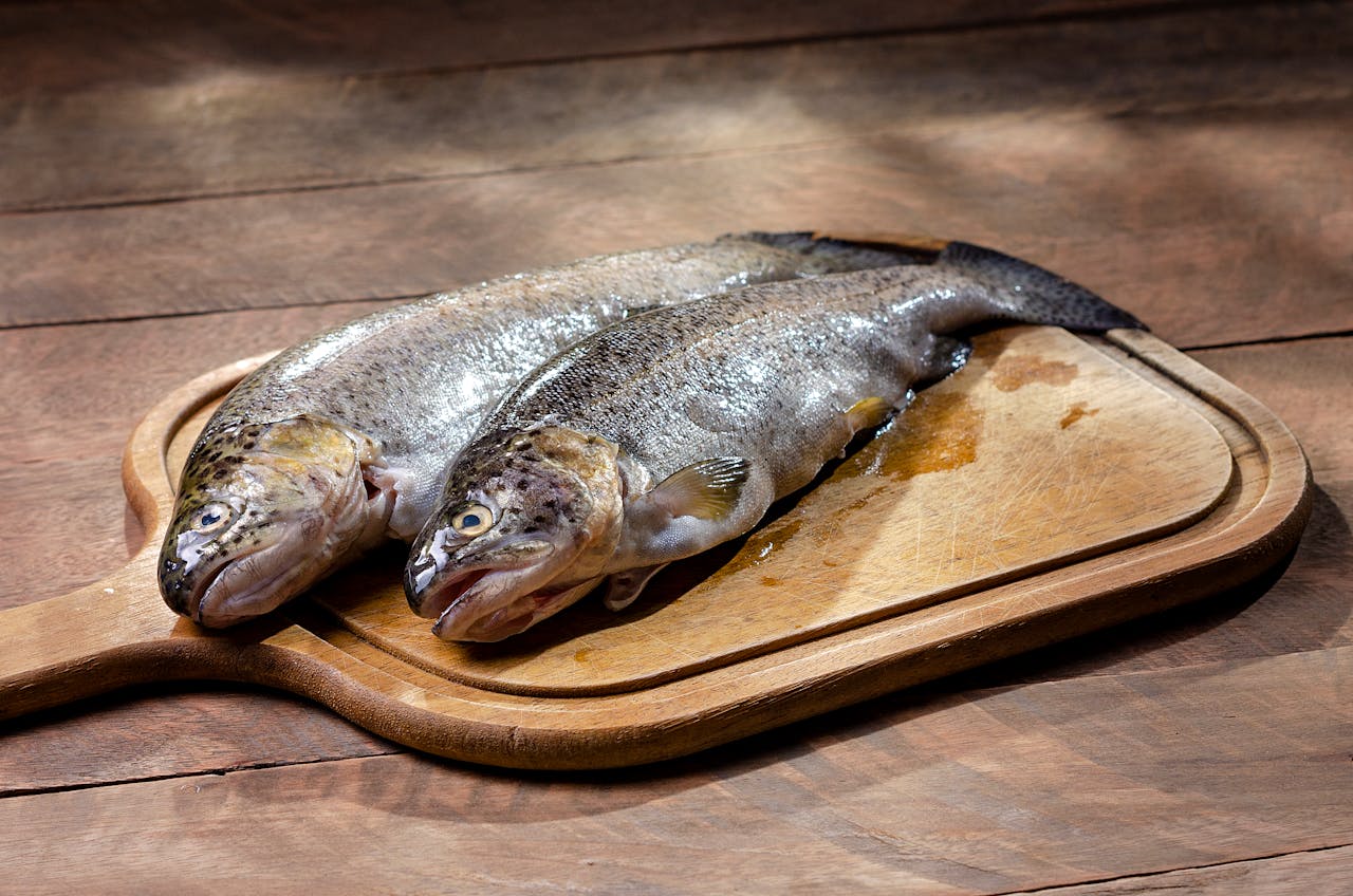 Fresh whole trout on a wooden cutting board, ideal for culinary uses.